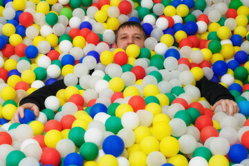 A happy man on a background of colorful plastic balls. A festive event.