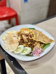 Spicy Acehnese fried rice (nasi goreng Aceh) served with shredded meat, sliced chilies, and aromatic herbs. September 28, 2025 - Karet, Indonesia