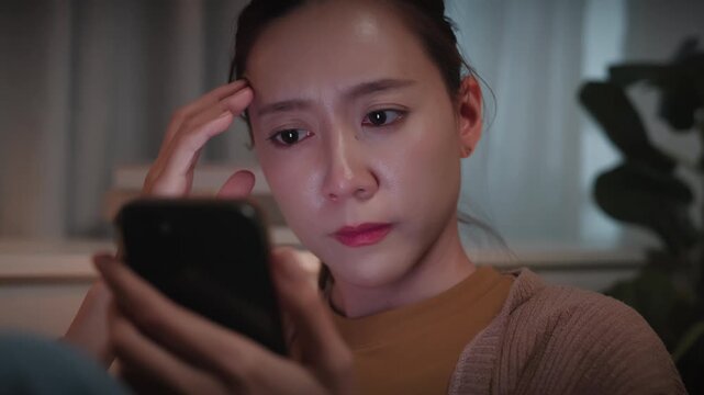 Worried girl reading online news in a smartphone late night	
