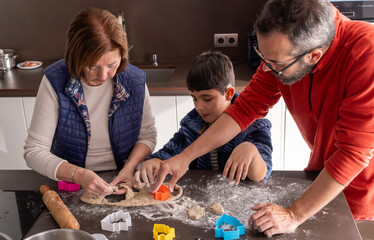 Multigenerational family cutting Christmas cookie dough on the kitchen counter with tree molds