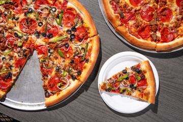 Large veggie pizza with one slice on a white plate 