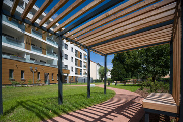 Wooden pergola in a green courtyard of a modern residential building