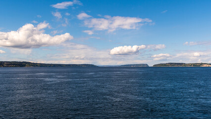 Puget Sound view from ferry between Mukilteo and Clinton, Washington, with islands on horizon and mostly sunny sky with scattered white clouds