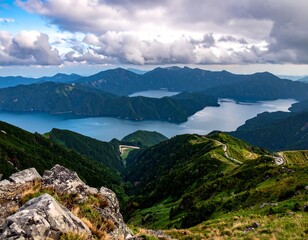 Panoramic mountain vista of deep blue lakes, winding roads, and lush green valleys