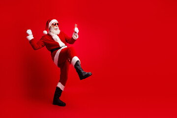 Santa Claus posing joyfully with his phone against a vibrant red background celebrating the festive Christmas season