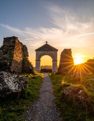 Ancient archway at sunset, surrounded by ruins.  A pathway leads to a stone archway, illuminated by a vibrant sunset.  Ruined stone walls border the path.  A cross atop the arch