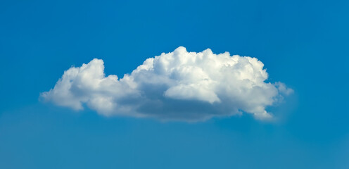 Isolated cascading cloud floating in the wind against blue sky. Big glowing clouds spreading on the deep blue sky sunny day. Nature concept background. Elegant landscape image