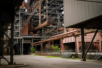 Naklejka premium Close-up of rusted metal pipelines and intricate steel walkways in an abandoned factory setting. Highlights industrial textures and architectural details.