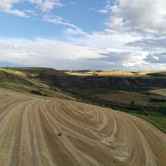 Rolling hills, agricultural land, dry fields,  hay bales, valley view