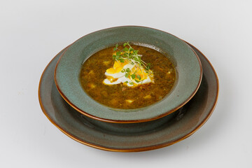 Hearty green soup with hard-boiled egg and sprouts