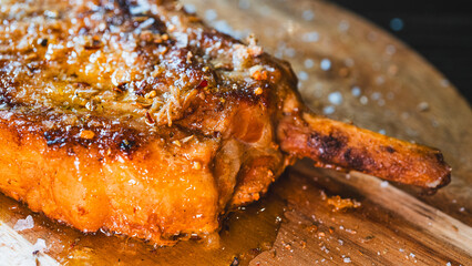 A perfectly grilled, juicy pork chop with the bone-in, seasoned with fresh herbs and garnished with flaky Maldon salt. This succulent cutlet is a hearty and delicious meal, captured steaming hot.
