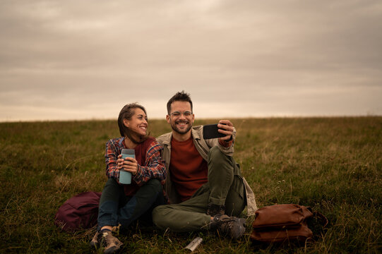 Hikers taking selfie while resting in meadow during hike