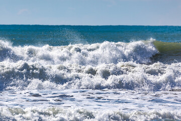 Fototapeta premium The raw power of a winter storm wave exploding onto the shoreline in a chaotic maelstrom of white water and spray, dramatically lit by the bright sun. Antalya, Turkey.