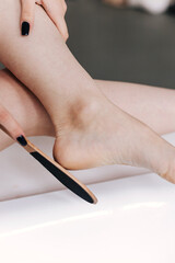 The young woman cleaning her feet, uses heel scrubber in bathroom