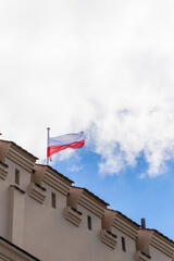 Polish flag on building, waving in the wind, white background with copy space