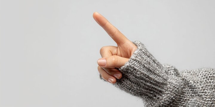 Close up of hand with raised pointing finger wearing a gray knitted sweater - Powered by Adobe
