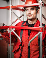 Young male construction worker posing with scaffolding indoors  