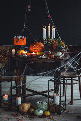 Elegant beautiful Halloween party table decor. Burning candled in vintage chandelier, handmade cake...