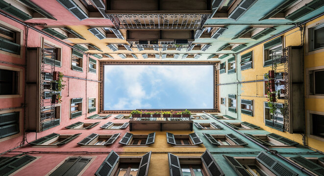 Symmetrical Low-Angle View of a Colorful Italian Courtyard with Open Sky
A striking low-angle perspective (worm's-eye view) looking straight up into the sky from the interior of a historical European
