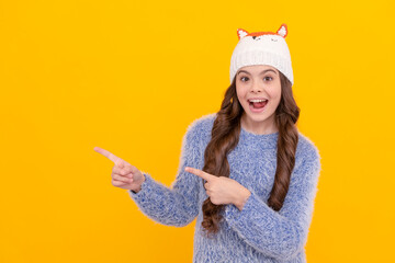 amazed kid point finger on copy space. female fashion model. teen girl in knitwear