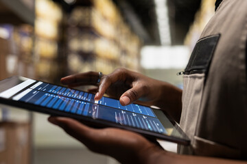 Close up of industrial operations worker verifying parcel shipment details on tablet, order...