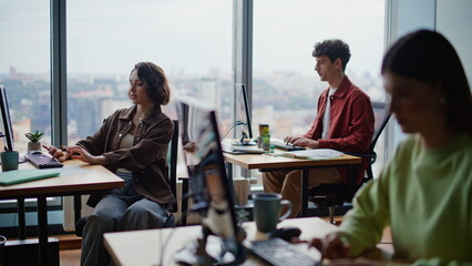 Young programmers coding computers sitting together at spacious coworking zone