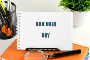 A notepad displays BAD HAIR DAY on a desk with pens, books, a plant and a magnifying glass, representing a common workplace issue. It conveys the idea of facing unexpected challenges