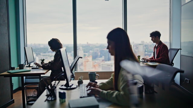 Programmers silhouettes coding computers together at spacious coworking zone