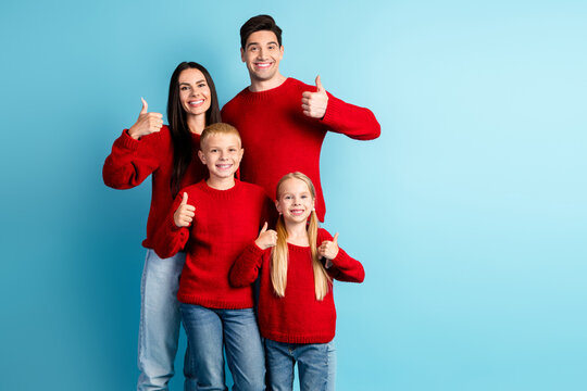 Cheerful family celebrating Christmas together wearing matching red sweaters with thumbs-up gesture on a blue background - Powered by Adobe