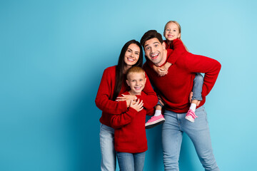 Joyful family in red sweaters smiling against a blue background, celebrating a cheerful Christmas...