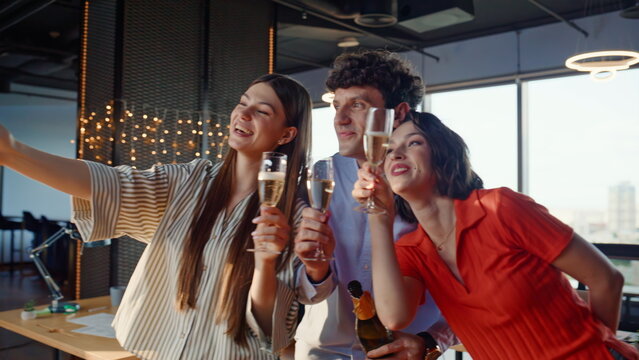 Office colleagues making selfie holding champagne glasses celebrating closeup
