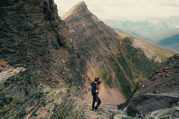 Hiker pauses on mountain trail, gazing at the vast