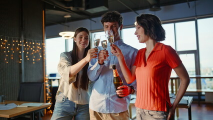 Joyful team clinking alcohol at corporate party laughing festive office closeup