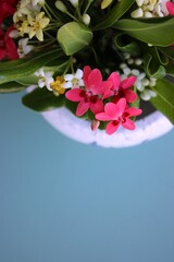 Vaso de cer&acirc;mica branco com flores do campo brancas e rosadas sobre fundo azul claro. Espa&ccedil;o vazio, mockup, foto vertical, White ceramic vase with white and pink wildflowers on a light blue background
