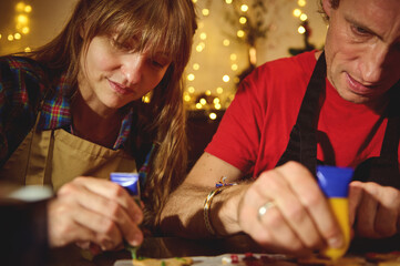 Couple Baking Together: Decorating Cookies in a Warm Christmas Kitchen with Fairy Lights