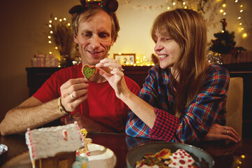Couple At Home Celebrating Christmas, Sharing Heart-Shaped Cookie During Cozy Festive Evening