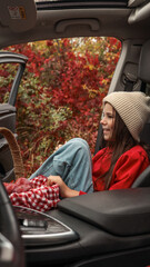 Girl enjoying a picnic in a car during autumn