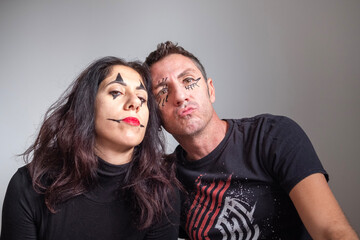 Obraz premium Husband and wife with face made up for Halloween portraits on light background. The man and woman are thirty-eight years old and of Caucasian origin