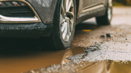 Car wheel in a puddle on a damaged road