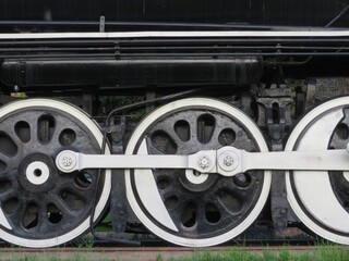 old metal black and white steam locomotive wheels on rail