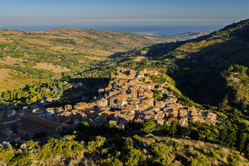 Obraz premium Aerial drone view of Collesano Sicilian mountain town at sunset with Basilica San Pietro church and historic stone streets in the Madonie Mountains, Sicily, Italy. Old mountain town in Sicily