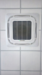 Ceiling-mounted cassette air conditioner unit with a white grille, providing climate control and comfort in a modern indoor environment.