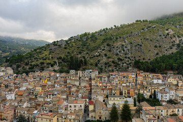Naklejka premium Aerial drone view of Collesano Sicilian mountain town at sunset with Basilica San Pietro church and historic stone streets in the Madonie Mountains, Sicily, Italy. Old mountain town in Sicily