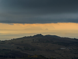 Aerial drone view of Capo Zafferano, a scenic Sicilian coastal promontory in the Metropolitan City of Palermo, Italy, featuring distant views of the Tyrrhenian Sea and the majestic Madonie Mountains