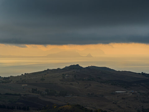 Aerial drone view of Capo Zafferano, a scenic Sicilian coastal promontory in the Metropolitan City of Palermo, Italy, featuring distant views of the Tyrrhenian Sea and the majestic Madonie Mountains