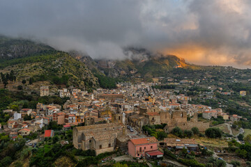 Obraz premium Aerial drone view of Collesano Sicilian mountain town at sunset with Basilica San Pietro church and historic stone streets in the Madonie Mountains, Sicily, Italy. Old mountain town in Sicily