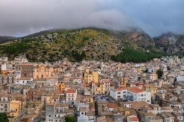 Fototapeta premium Aerial drone view of Collesano Sicilian mountain town at sunset with Basilica San Pietro church and historic stone streets in the Madonie Mountains, Sicily, Italy. Old mountain town in Sicily