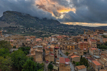 Aerial drone view of Collesano Sicilian mountain town at sunset with Basilica San Pietro church and historic stone streets in the Madonie Mountains, Sicily, Italy. Old mountain town in Sicily