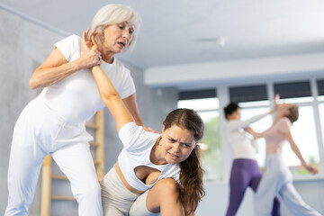 Determined mature woman attending self-defense classes at training center, applying arm lock...