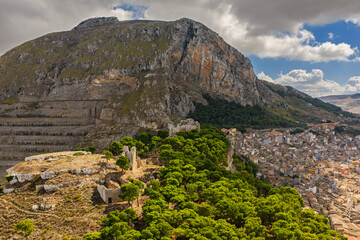 Aerial drone view of Caltavuturo, a historic Sicilian mountain town in Palermo, Italy, featuring its medieval castle, rugged surrounding cliffs, and scenic landscapes of the Madonie Mountains